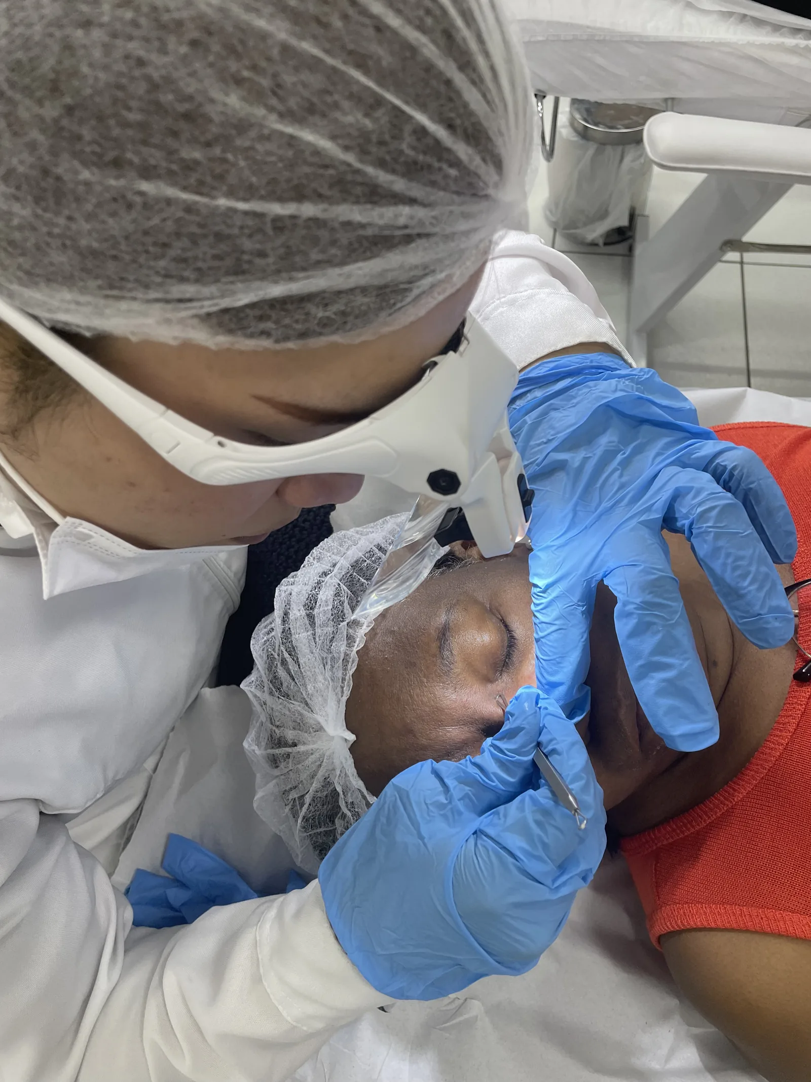 Aluna usando lupa e luvas durante a extração em aula prática
